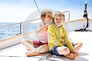 Two little kid boys, best friends enjoying sailing boat trip. Family vacations on ocean or sea on sunny day. Children