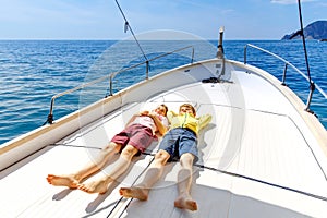 Two little kid boys, best friends enjoying sailing boat trip. Family vacations on ocean or sea on sunny day. Children