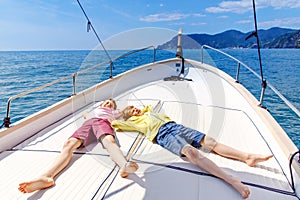 Two little kid boys, best friends enjoying sailing boat trip. Family vacations on ocean or sea on sunny day. Children