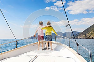 Two little kid boys, best friends enjoying sailing boat trip. Family vacations on ocean or sea on sunny day. Children