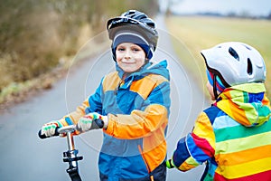 Two little kid boys, best friends riding on scooter in park