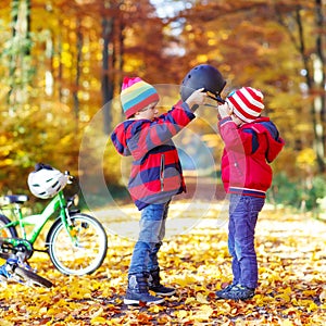 Two little kid boys with bicycles in autumn forest