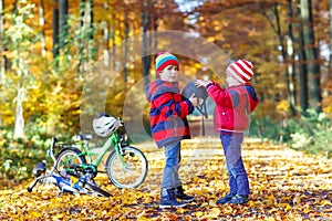 Two little kid boys with bicycles in autumn park