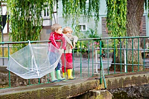 Two little kid boys with big umbrella outdoors