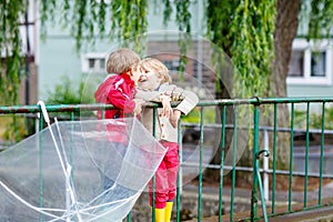 Two little kid boys with big umbrella outdoors