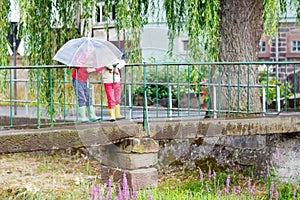 Two little kid boys with big umbrella outdoors