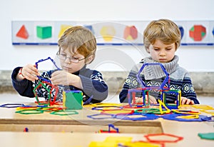 Two little kid boys building geometric figures