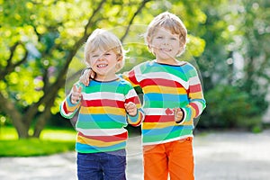 Two little kid boys in colorful clothing walking hand in hand