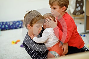 Two little kid boys hugging with newborn baby girl, cute sister.