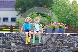 Two little kid boys sitting together on stone bridge