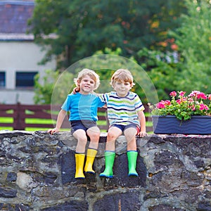 Two little kid boys sitting together on stone bridge