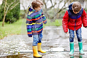 Two little kid boys on way to school walking during sleet, rain and snow on cold day. Children, best friends and