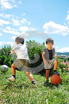 Two little kids with basketball and football