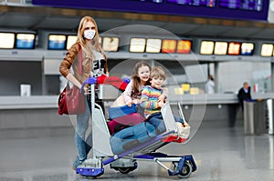 Two little kids, boy and girl and mother in medical mask at airport. Children, family travel by plane during corona