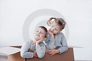 Two a little kids boy and girl playing in cardboard boxes. Concept photo. Children have fun