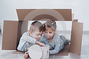 Two a little kids boy and girl playing in cardboard boxes. Concept photo. Children have fun