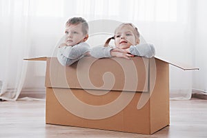 Two a little kids boy and girl playing in cardboard boxes. Concept photo. Children have fun