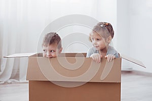 Two a little kids boy and girl playing in cardboard boxes. Concept photo. Children have fun
