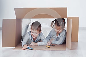 Two a little kids boy and girl playing small cars in cardboard boxes. Concept photo. Children have fun. Concept photo