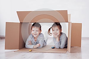 Two a little kids boy and girl playing small cars in cardboard boxes. Concept photo. Children have fun. Concept photo