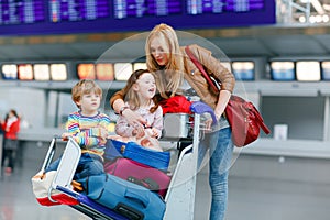 Two little kids, boy and girl, siblings and mother at the airport. Children, family traveling, going on vacation by