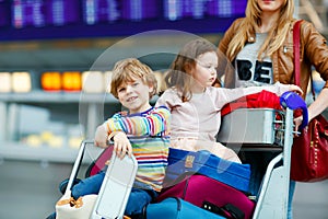Two little kids, boy and girl, siblings and mother at the airport. Children, family traveling, going on vacation by