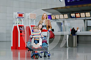 Two little kids, boy and girl, siblings and mother at the airport. Children, family traveling, going on vacation by