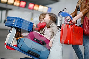 Two little kids, boy and girl, siblings and mother at the airport. Children, family traveling, going on vacation by