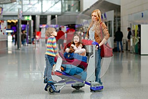 Two little kids, boy and girl, siblings and mother at the airport. Children, family traveling, going on vacation by