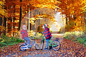 Two little kids boys, best friends in autumn forest with bikes. Active siblings, children with bicycles. Boys in