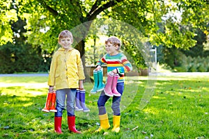 Two little kids boys, cute siblings with lots of colorful rain boots. Children in different rubber boots and jackets