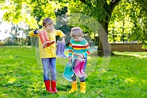 Two little kids boys, cute siblings with lots of colorful rain boots. Children in different rubber boots and jackets