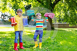 Two little kids boys, cute siblings with lots of colorful rain boots. Children in different rubber boots and jackets