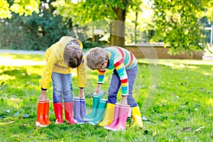 Two little kids boys, cute siblings with lots of colorful rain boots. Children in different rubber boots and jackets