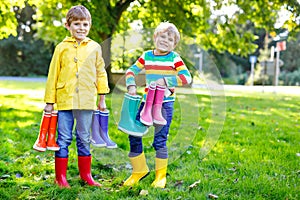 Two little kids boys, cute siblings with lots of colorful rain boots. Children in different rubber boots and jackets