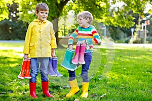 Two little kids boys, cute siblings with lots of colorful rain boots. Children in different rubber boots and jackets