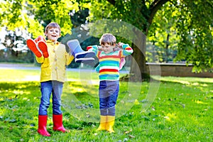 Two little kids boys, cute siblings with lots of colorful rain boots. Children in different rubber boots and jackets