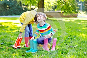 Two little kids boys, cute siblings with lots of colorful rain boots. Children in different rubber boots and jackets