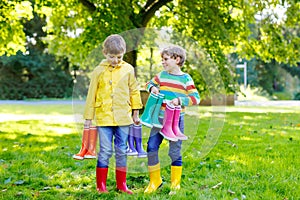 Two little kids boys, cute siblings with lots of colorful rain boots. Children in different rubber boots and jackets