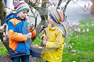 Two little kids boys and friends making traditional Easter egg hunt