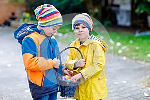 Two little kids boys and friends making traditional Easter egg hunt