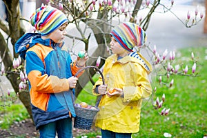 Two little kids boys and friends making traditional Easter egg hunt