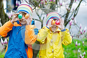 Two little kids boys and friends making traditional Easter egg hunt