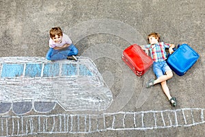 Two little kids boys having fun with train picture drawing with colorful chalks on asphalt. Children having fun with