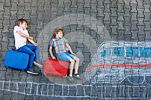 Two little kids boys having fun with train picture drawing with colorful chalks on asphalt. Children having fun with