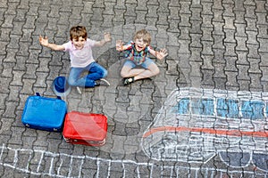 Two little kids boys having fun with train picture drawing with colorful chalks on asphalt. Children having fun with