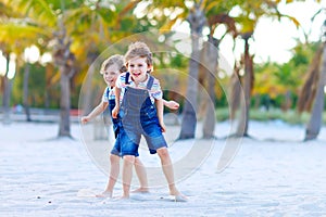 Two little kids boys having fun on tropical beach, happy best friends playing, friendship concept. Siblings brothers