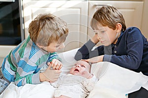 Two little kids boys with newborn baby girl, cute sister. Siblings. Brothers and baby playing with colorful toys and