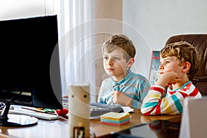 Two little kids boys playing computer games on desktop pc. Modern addict activity for children. Siblings and friends