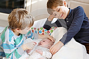 Two little kids boys playing with newborn baby sister girl